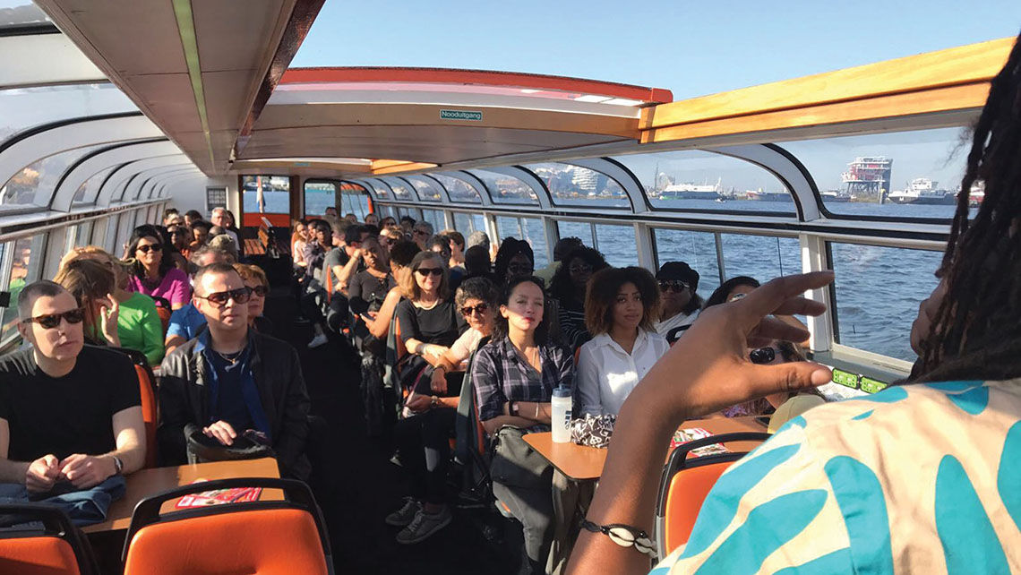A group sails on a saloon boat while on a Black heritage tour in Amsterdam.