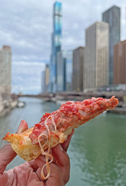 Enjoying a slice of deep-dish pizza on the DuSable Bridge, overlooking the Chicago River.
