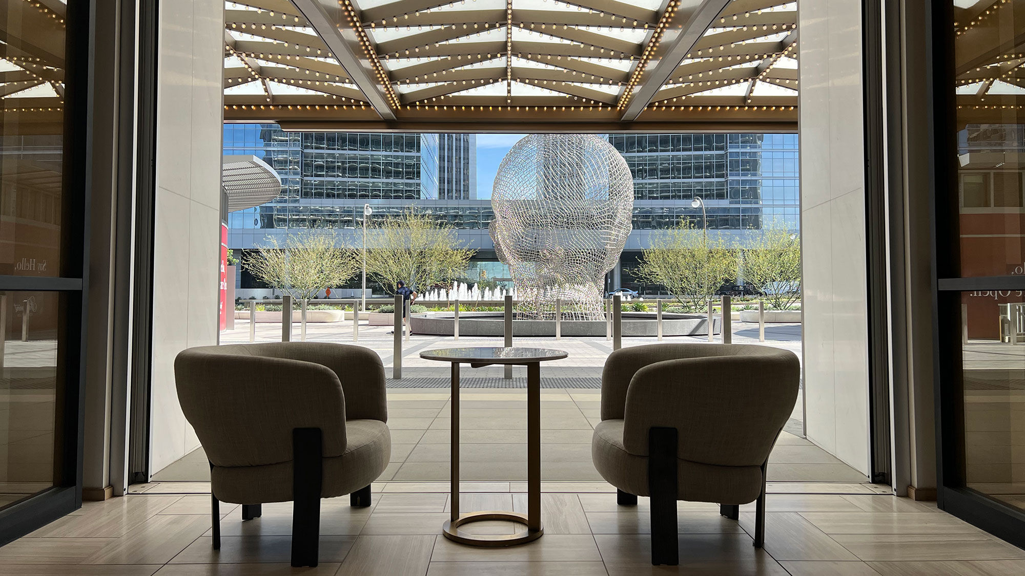 A lobby view of a sculpture by Jaume Plensa. Glass walls in the hotel's lobby sink into the floor, creating an indoor extension of the outdoors.