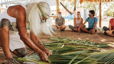 Hawaii visitors learning how to weave the leaves of a niu (coconut) tree.