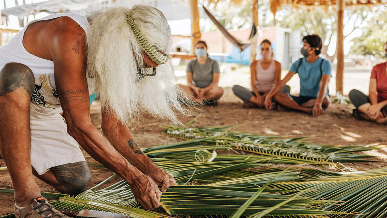 Hawaii visitors learning how to weave the leaves of a niu (coconut) tree.