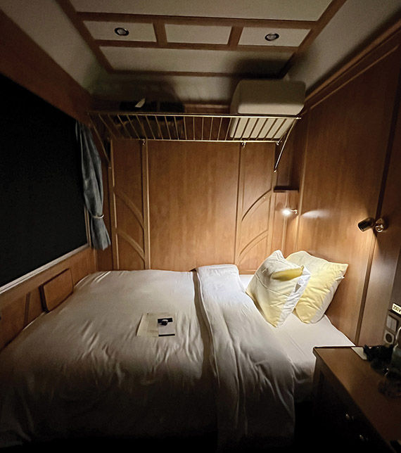 A sleeper cabin onboard the train with the bed pulled out for nightly turndown service.