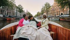 An image from Delta's Faces of Travel open-source library shows Black girlfriends enjoying a canal cruise in Amsterdam.