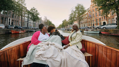 An image from Delta's Faces of Travel open-source library shows Black girlfriends enjoying a canal cruise in Amsterdam.
