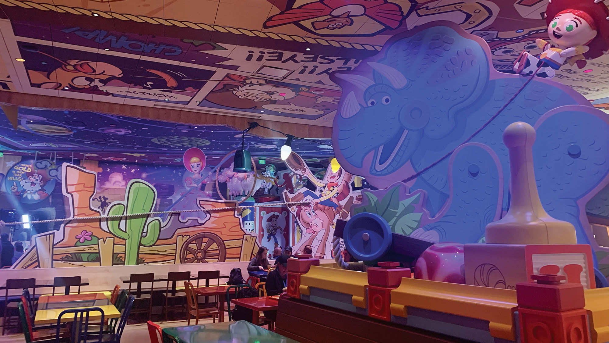 Inside the restaurant, guests become the size of toys and are greeted by larger-than-life toy pieces, including Jessie riding Trixie the triceratops.