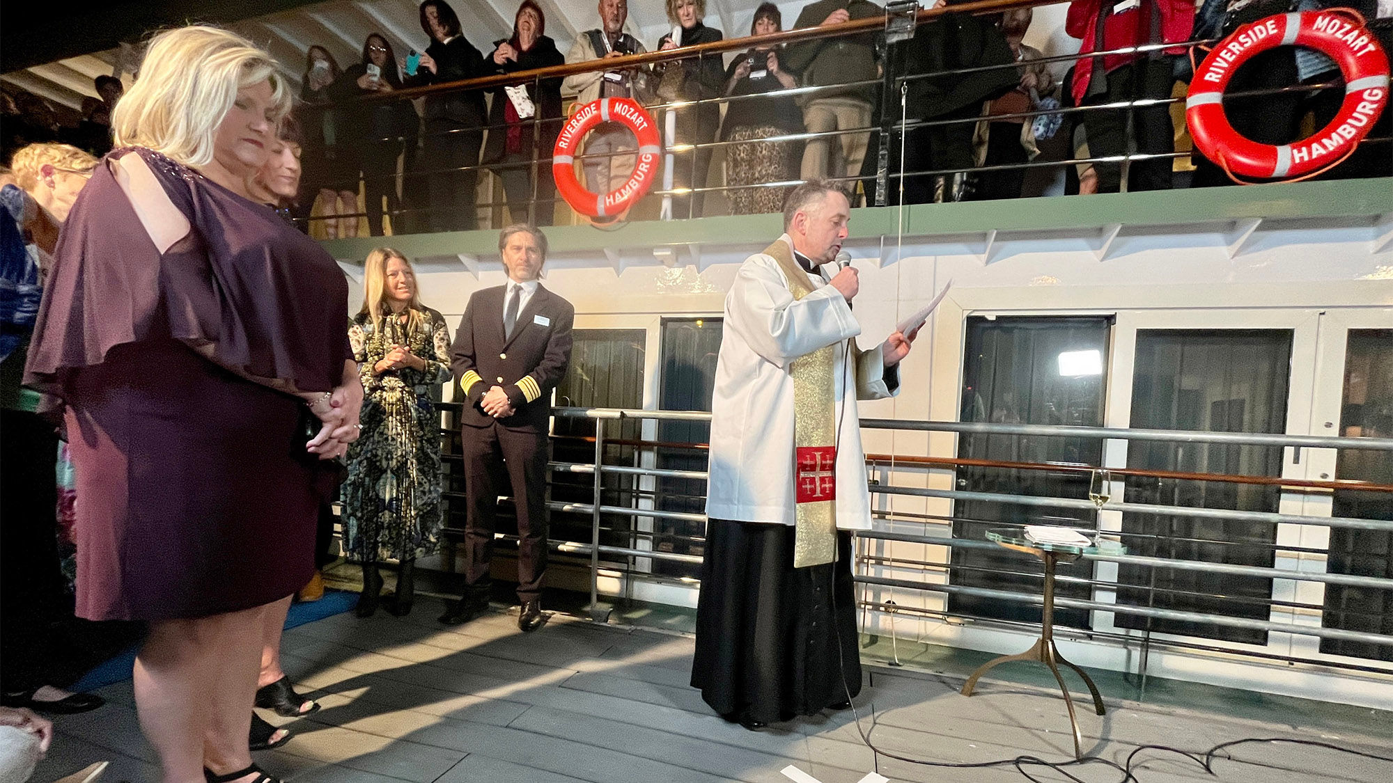 A Hungarian priest blesses the Riverside Mozart alongside godmother Tiffany Hines, left, of Global Escapes in Athens, Ga.