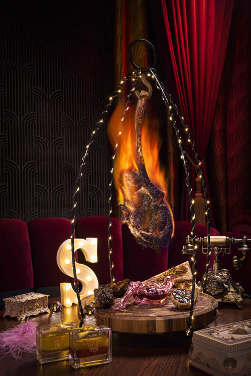 The Super Tomahawk is a bone-in ribeye hung from a trellis with lights. The Super Tomahawk is a bone-in ribeye hung from a trellis with lights.