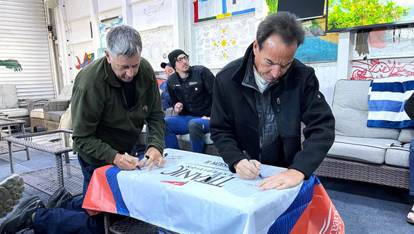 Stephen, a member of the Royal Australian Navy (left) and travel advisor Craig Curran of DePrez Travel Bureau sign the OceanGate Mission 2 flag. Stephen, a member of the Royal Australian Navy (left) and travel advisor Craig Curran of DePrez Travel Bureau sign the OceanGate Mission 2 flag.