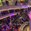 The cruise director speaks to guests in the Carnival Venezia's atrium to recognize the ship's officers.