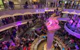 The cruise director speaks to guests in the atrium on the Carnival Venezia to recognize the ship's officers.