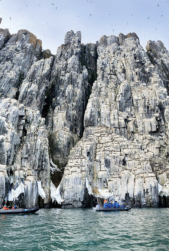 Guests on the National Geographic Endurance cruise at the cliffs of Alkefjellet in Svalbard.