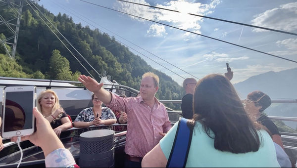 Michael Thomas, tour director for Trafalgar, guides advisors on the open air Cabrio Cable Car from Stans up to Mount Stanserhorn on Lake Lucerne in Switzerland.