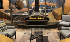 A water-vapor "fireplace" in the Seabourn Pursuit's cozy Exploration Lounge; behind it is a panel that nods to the ship's deployment.