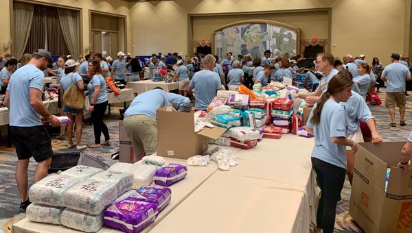 Attendees of Signature Travel Network’s Owner’s Meeting sort donations. Attendees of Signature Travel Network’s Owner’s Meeting sort donations.