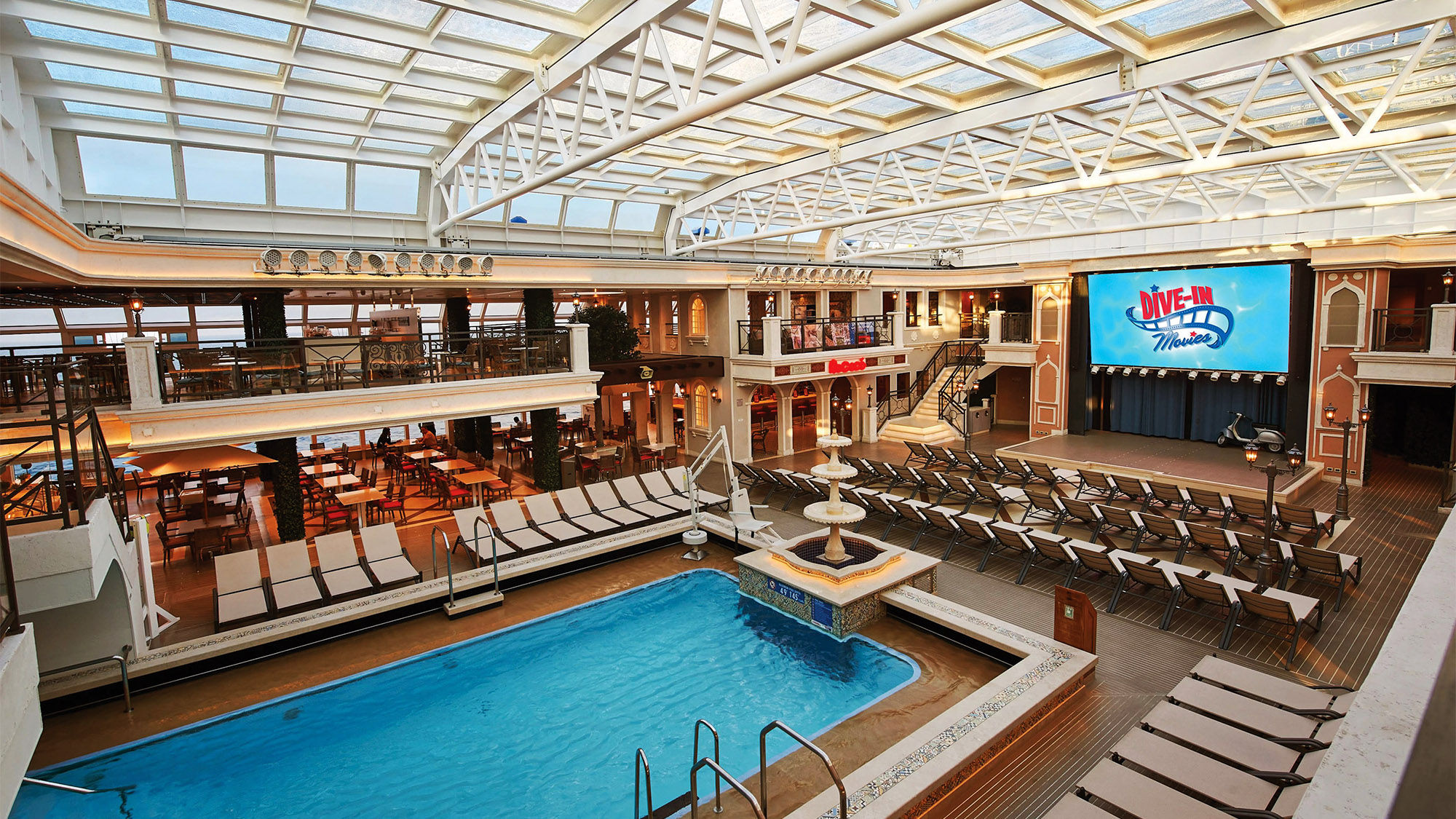 The Carnival Venezia's Lido pool is under a retractable roof and is boxed in by a bar, coffee shop, two takeaway food venues, tables and a second-floor overlook.