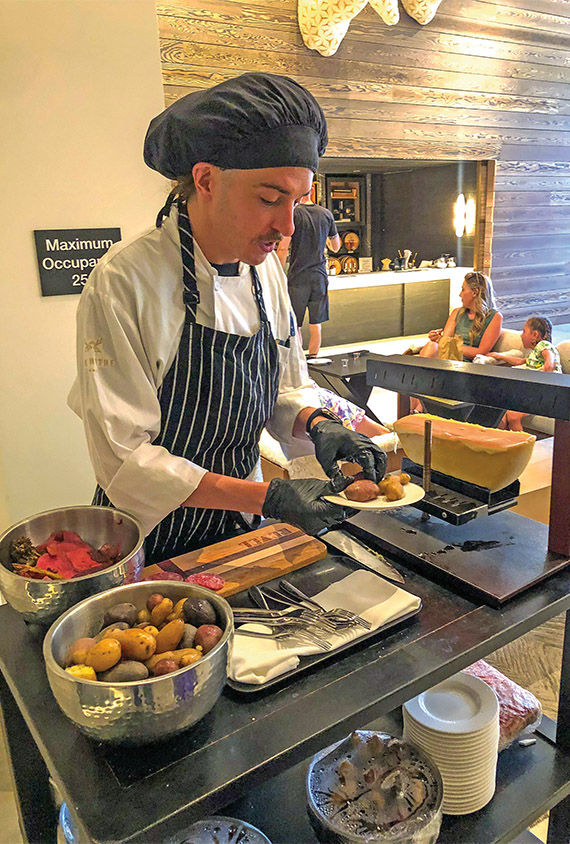 A pop-up raclette station in the resort's lobby with complimentary plates of melted cheese on a bed of meat, potatoes and veggies.