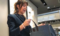 Maria Antonietta Franzini, a sales agent at The Journey shop on the Explora I, displays a women's handbag that sells for 535 euros.