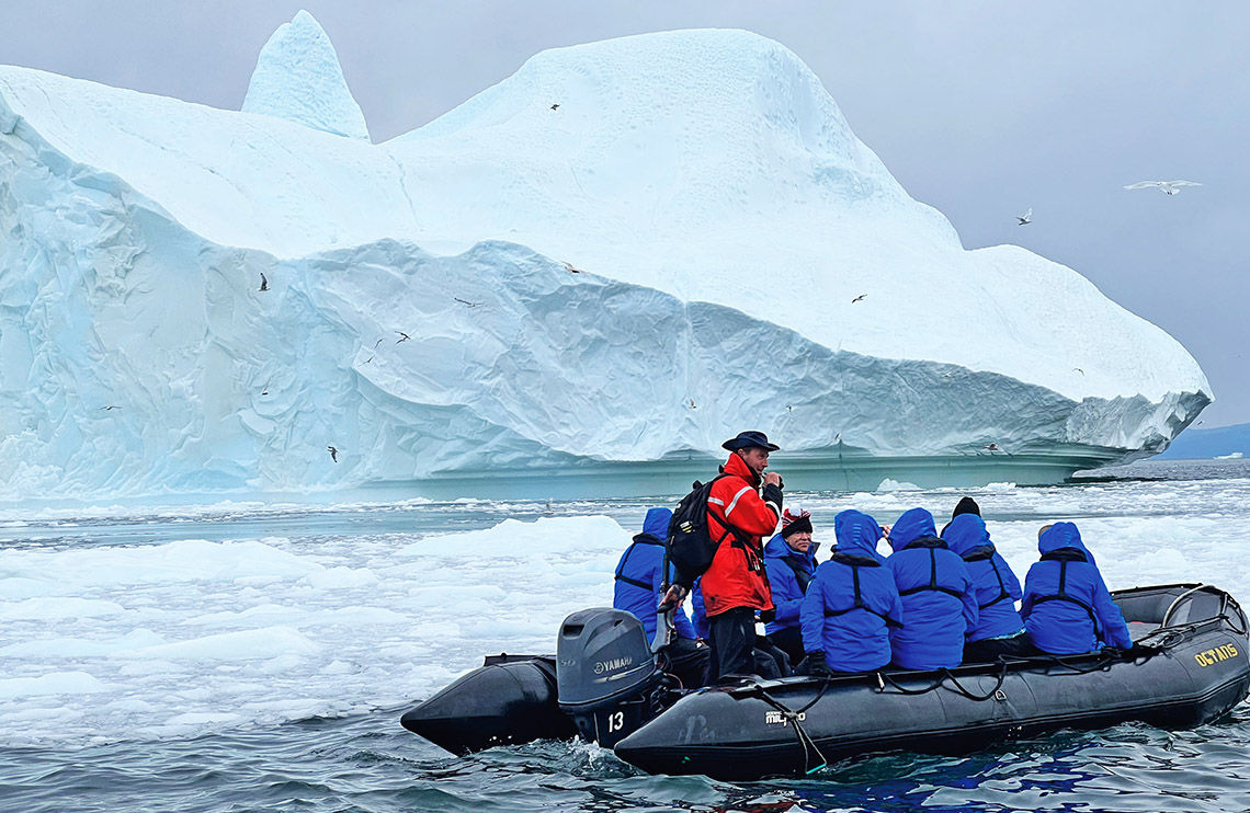 Adventure Canada expedition team leader Chris Dolder guides guests past an iceberg in Ilulissat, Greenland, where guests visited Sermeq Kujalleq, one of the most active and fastest glaciers in the world.
