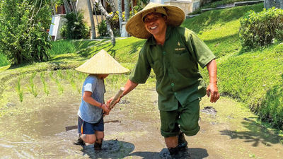 Travel Weekly editor Christina Jelski's son planting rice seedlings with Wirawan, an agricultural expert at the Four Seasons Resort Bali at Sayan.