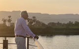 Viking Aton guest takes in the scenic views of sailing on Egypt's Nile River at sunset.