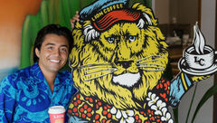 Lion Coffee tour guide Makana David stands next to the company’s familiar lion character.