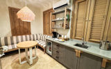 A kitchenette area in a beachfront one-bedroom villa suite accommodation features a stocked bar and coffee station, as well as a kitchen table with banquette seating.