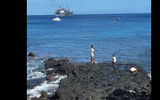 Boys fishing off a rock on Tahuata; the Aranui 5 is in the background.