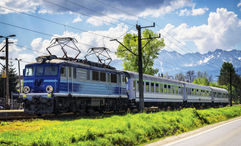 A passenger train in Poland, with the Tatra Mountains in the background.