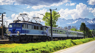 A passenger train in Poland, with the Tatra Mountains in the background.