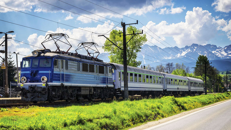 A passenger train in Poland, with the Tatra Mountains in the background.