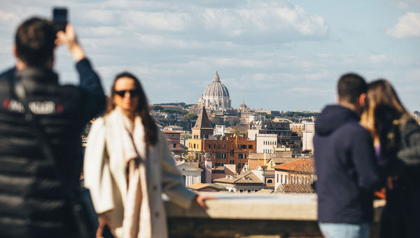 A tourist poses for a photo with St. Peter's Basilica in the background.