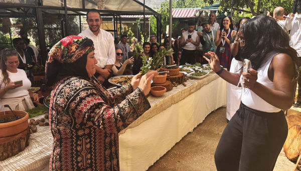 A woman who works at Beit Khayrat Souf dances with a G Adventures traveler in Souf, Jordan.