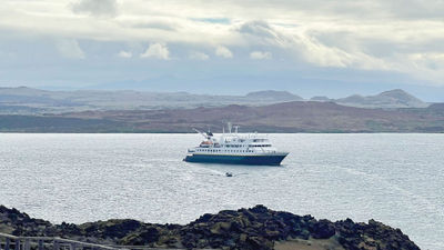 The Gemini is anchored in a bay while passengers depart for a hike.
