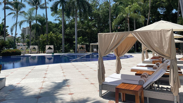 Palm trees and daybeds surround the pool at Casa Velas.