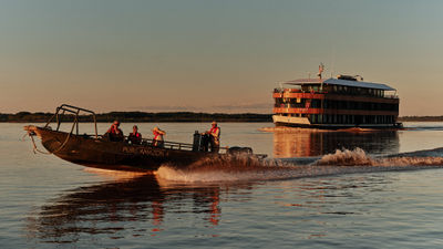 A skiff excursion with the Pure Amazon in the background. The Pure Amazon is Abercrombie & Kent's first South American riverboat.