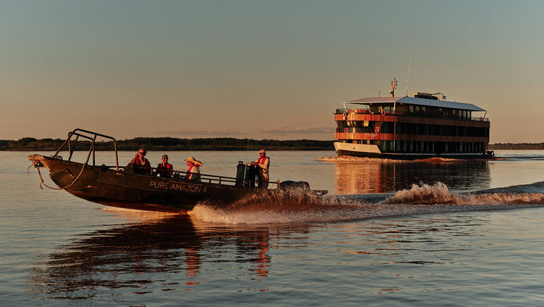 A skiff excursion with the Pure Amazon in the background. The Pure Amazon is Abercrombie & Kent's first South American riverboat.