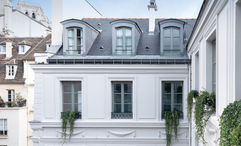 The facade of the Maison Colbert hotel. One of the towers of Notre Dame can be seen in the background.
