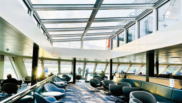 Large windows and a glass ceiling in the lounge of Havila Voyages' Pollux showcase views of the fjords. Large windows and a glass ceiling in the lounge of Havila Voyages' Pollux showcase views of the fjords.