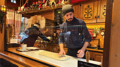 A pastry maker rolls out chimney cake dough at the Passauer Christkindlmarkt in Passau, Germany.
