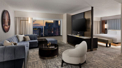 A remodeled executive king suite living room at the MGM Grand features walnut finishes and vibrant carpeting.