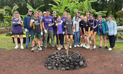 A group of students on the Imu Mea Ai tour complete building an imu, a traditional Hawaiian underground oven.