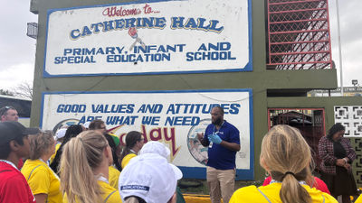 A group of travel advisors listen to instruction outside of Catherine Hall Primary School, where they painted and organized donations.