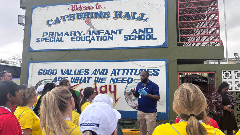 Volunteering travel advisors listen to instructions outside of Catherine Hall Primary School, where they paint and organize donations.