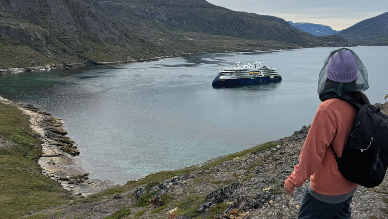 A passenger on a National Geographic-Lindblad Expeditions Greenland cruise looks down at the National Geographic Resolution during a hike.