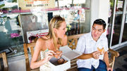A couple enjoys malasadas, a Portuguese pastry similar to a doughnut, at Leonard's Bakery, which is on the Taste of Oahu food tour offered by Aunty Sweetie's Hawaiian Tours.