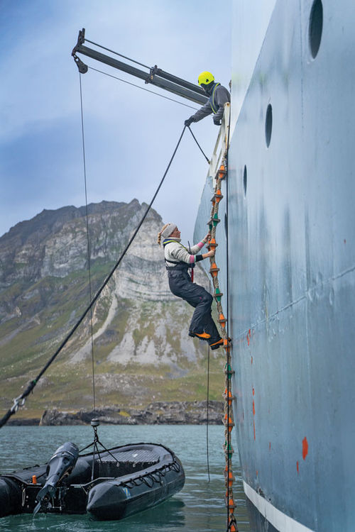 A passenger climbs a rope ladder onto the Polarfront during an Arctic sailing. A passenger climbs a rope ladder onto the Polarfront during an Arctic sailing.