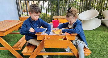 Two of the author's children hunt for buried treasure on the shaded patio at the Kids Club at Conrad Orlando.