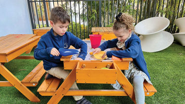 Two of the author's children hunt for buried treasure on the shaded patio at the Kids Club at Conrad Orlando.
