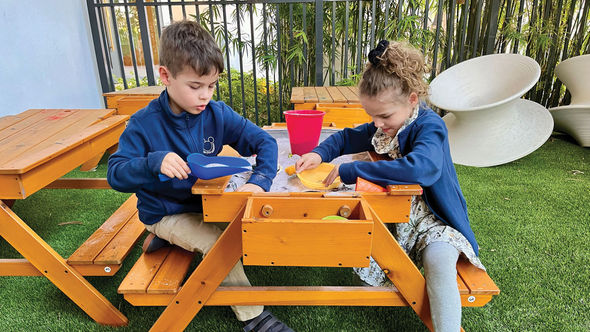Two of the author's children hunt for buried treasure on the shaded patio at the Kids Club at Conrad Orlando.