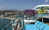 Lounge chairs in Chill Island on the Legend of the Seas, with Malaga, Spain in the background.